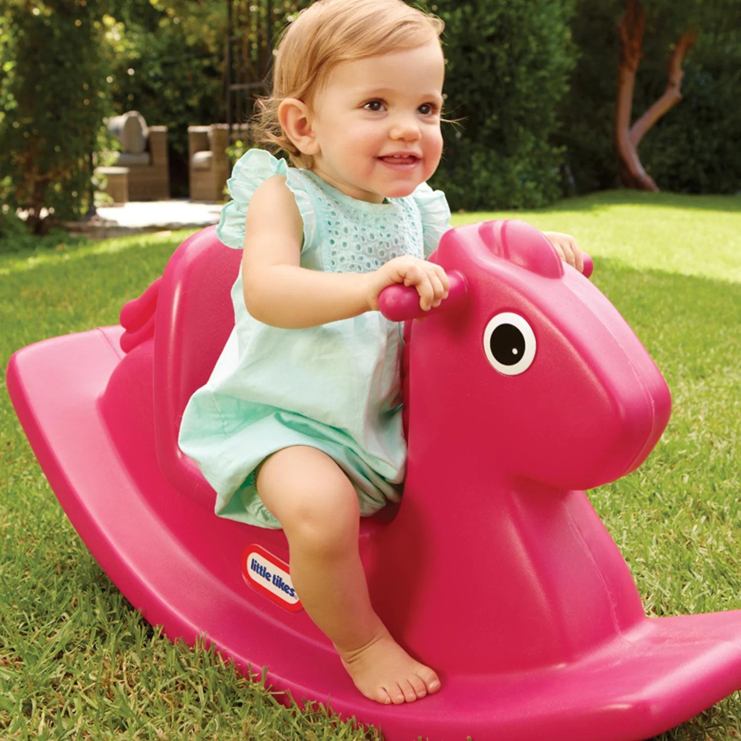 Magenta rocking horse toy being used by a sitting baby, with front face eye