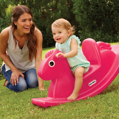 Magenta rocking horse with baby rider and smiling adult beside it