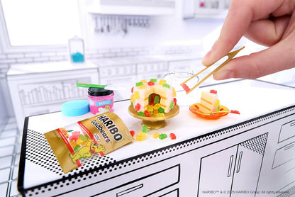 Hand assembling mini candy pieces on gold tray from Haribo miniature kit