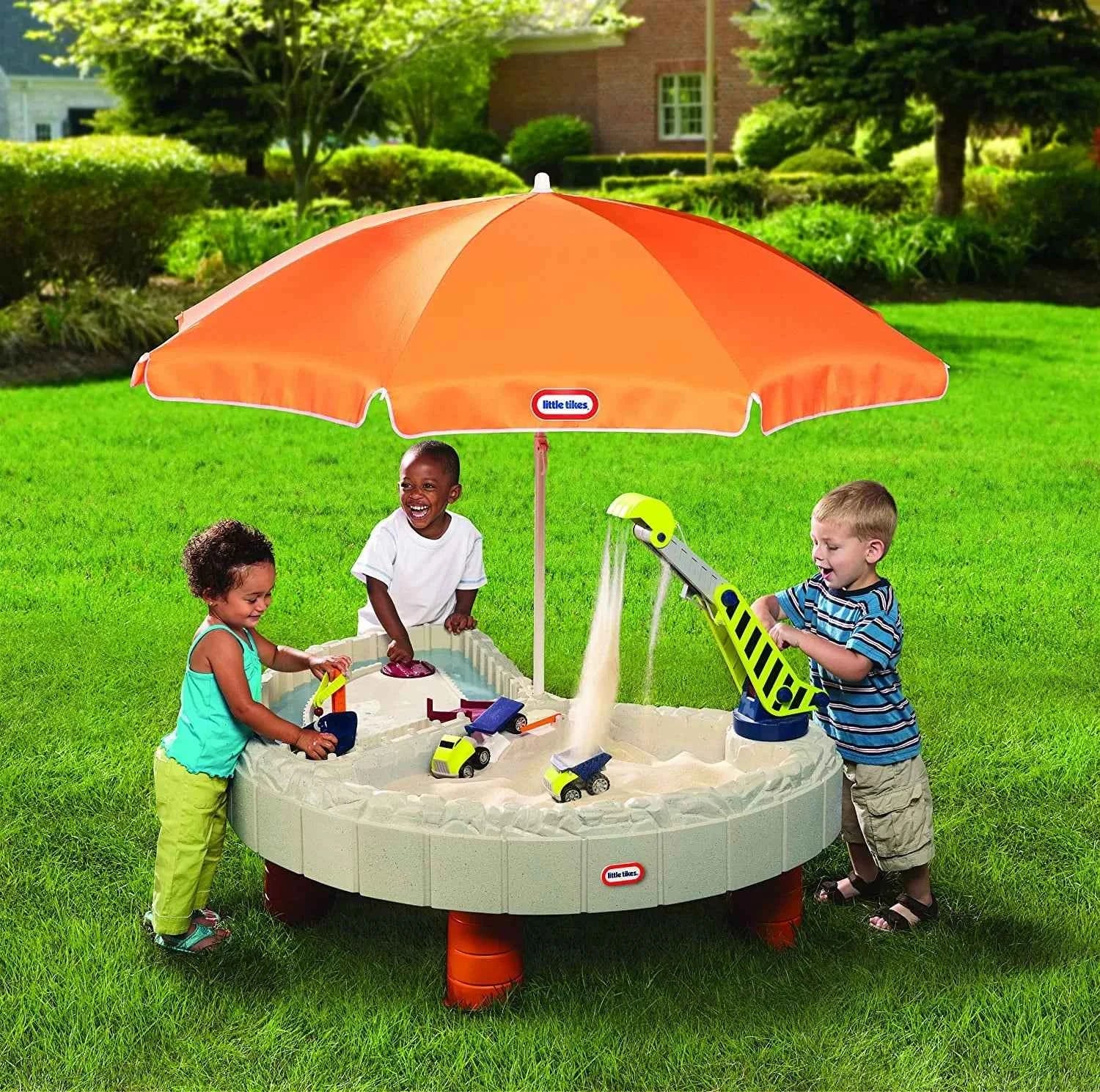 Construction sand and water table with orange umbrella over round sand pit