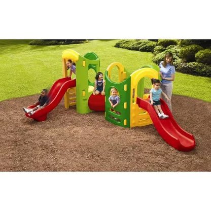 Plastic playground playset with red slides and green-yellow towers, kids climbing