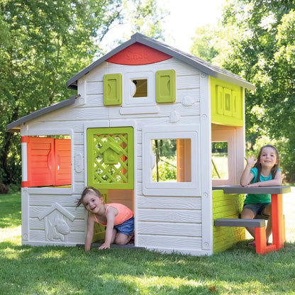 Kids' playhouse kitchen with white siding, lime panels, red doors, gray roof