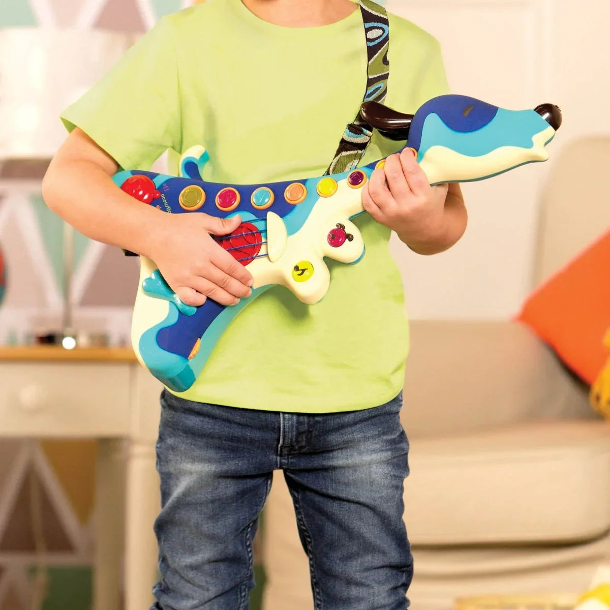 Child holding a blue toy guitar with colorful knobs and a patterned strap