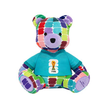 Colorful bear plush in teal shirt with FIFA logo badge, multicolor patchwork fur.