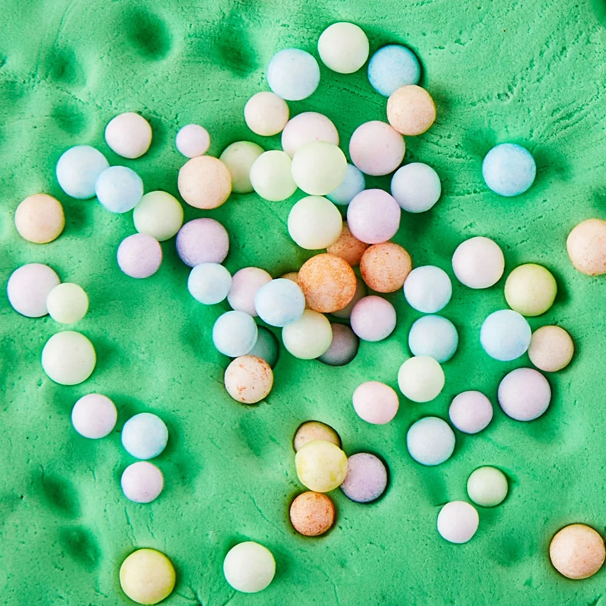 Pastel air-dry clay balls scattered on a green play surface