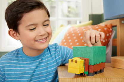 Blocky green and orange dinosaur toy with yellow head on wooden base