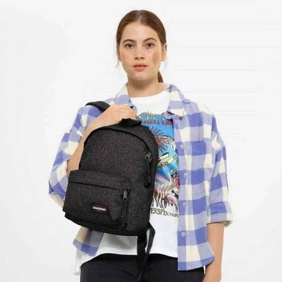 Black speckled mini backpack held over shoulder, front zip pocket and side zipper.