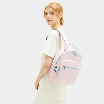Seoul S mini backpack on model, pale pink with teal accents and plush keychain