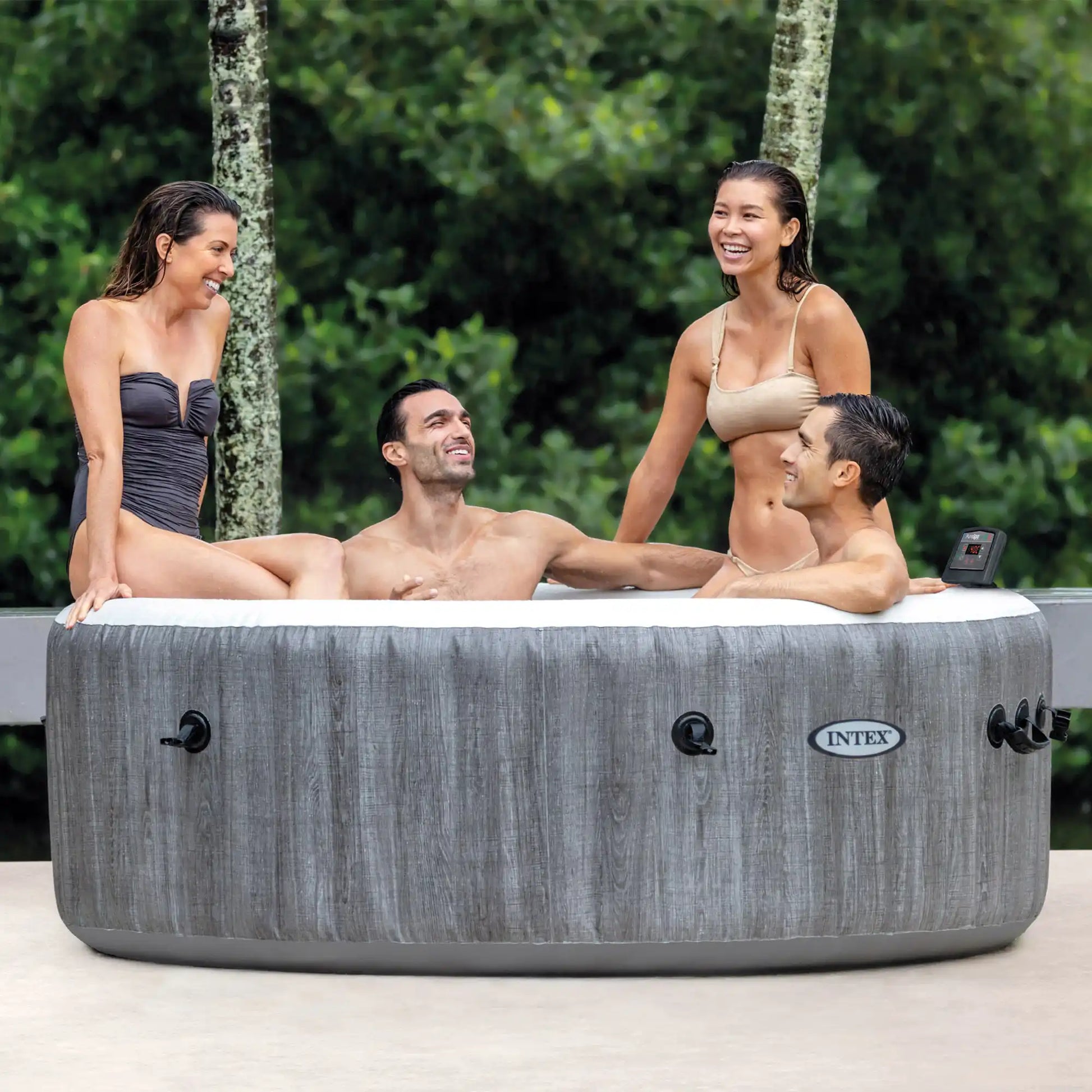Gray round inflatable spa with white top; four people seated and smiling