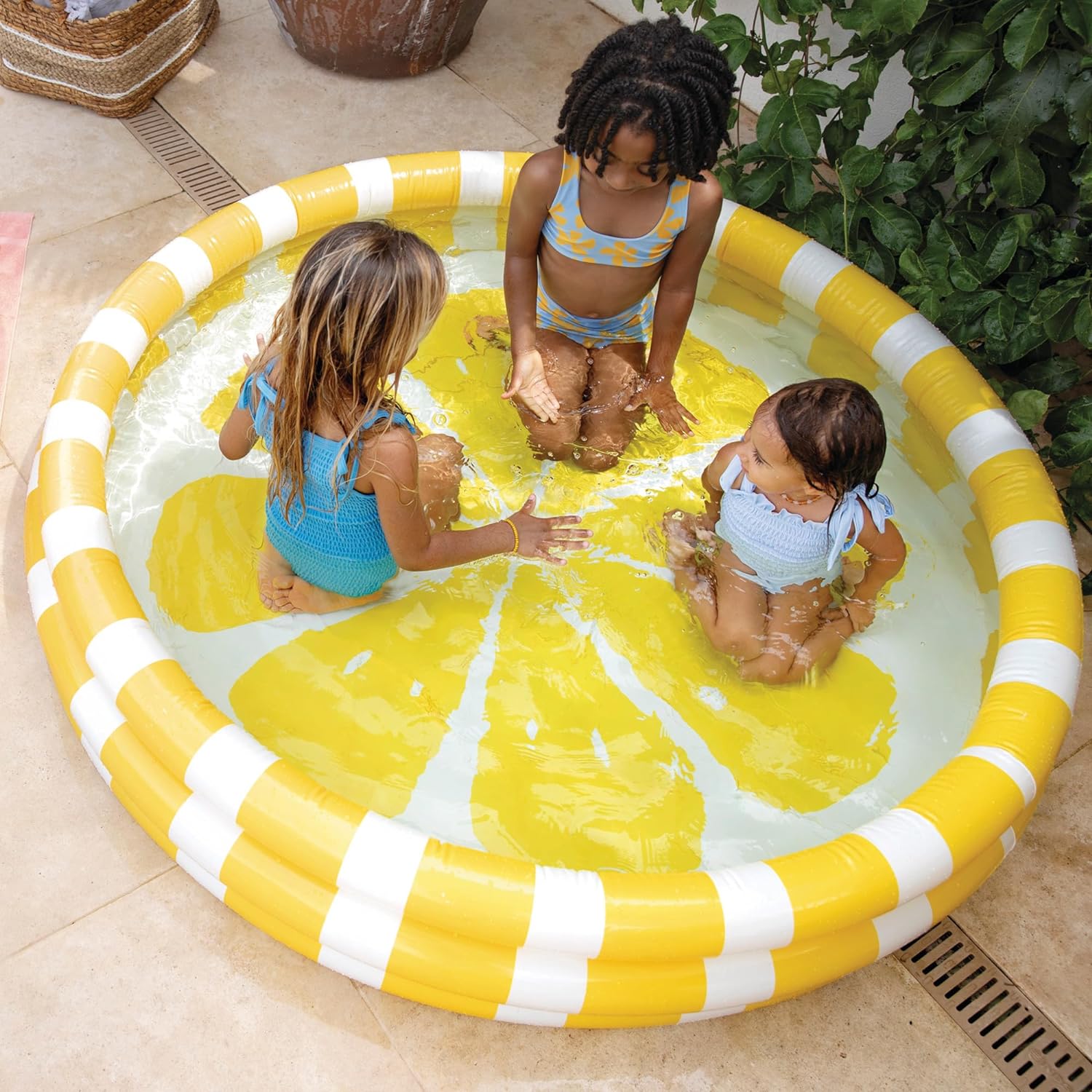 Yellow and white striped inflatable pool with three children playing in water