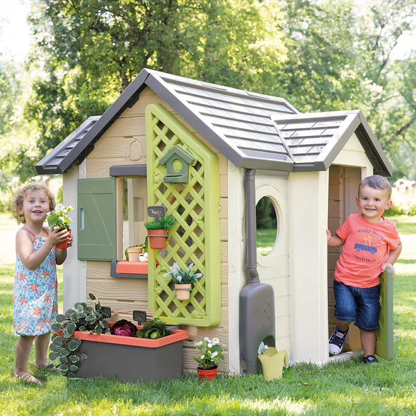 Plastic garden playhouse with open front, green door panel, gray roof, and shutters