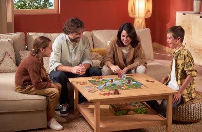 Dinosaurs board game on a table with players seated, hands on the board.