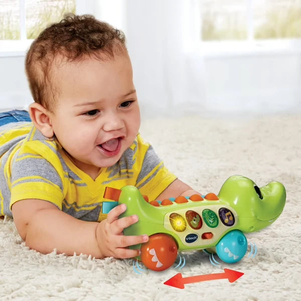 Green pull-along crocodile toy with orange head, blue feet, and circular light-up buttons