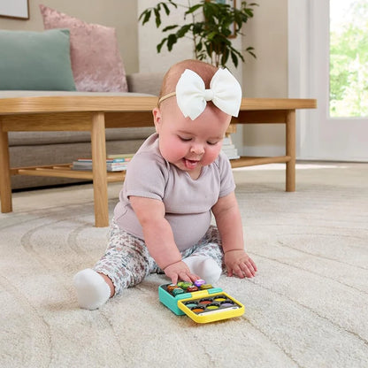 Baby playing with colorful learning tablet toy on the floor, matching key panel.