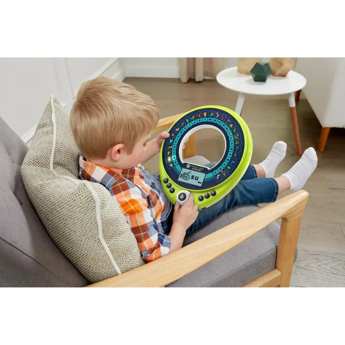 Letter ring toy in child’s hands with blue letter display and green rim