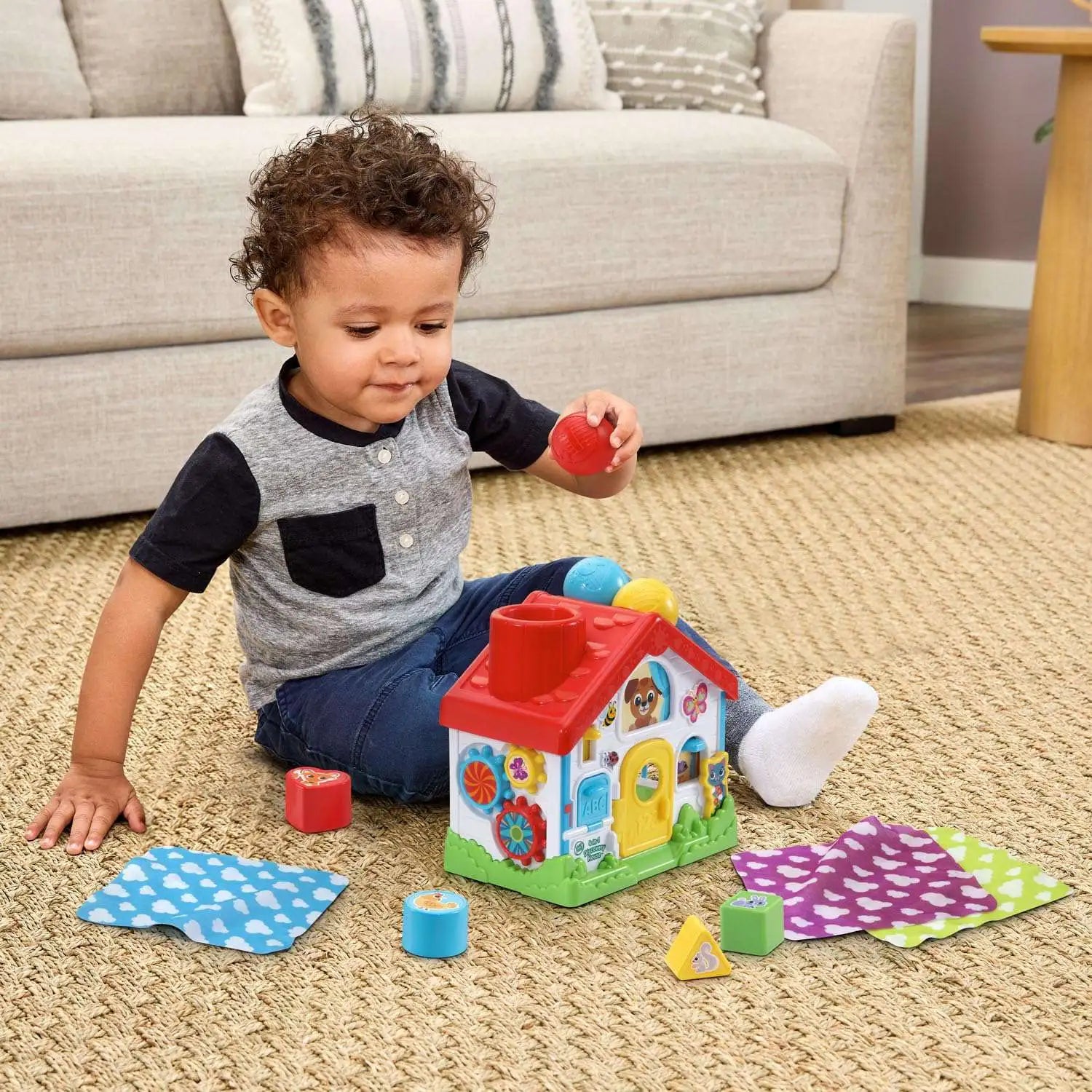 Baby discovery toy playhouse with colorful blocks and balls, held by a toddler
