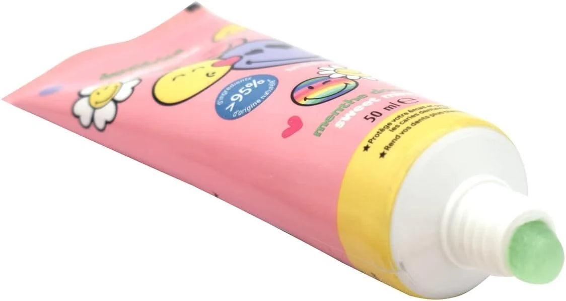 Toothpaste tube angled with mint-colored cap and pink tube with smiley icons