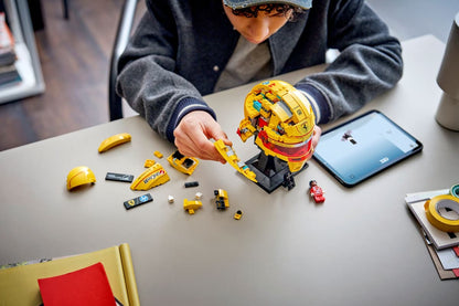 Yellow racing helmet model on black stand with small racing figure and loose parts