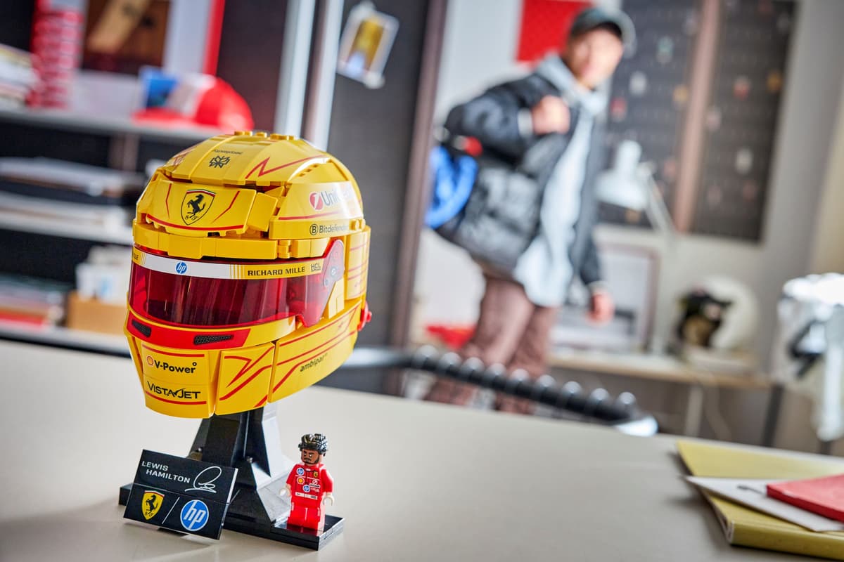 Yellow racing helmet on black stand with small racing figure on desk