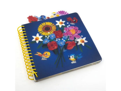 Blue spiral-bound notebook with floral bouquet, birds, and butterfly design on cover