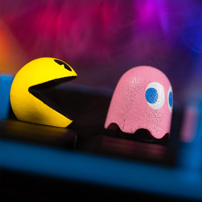 Pac-Man and ghost character pieces on a board, including pink and yellow faces