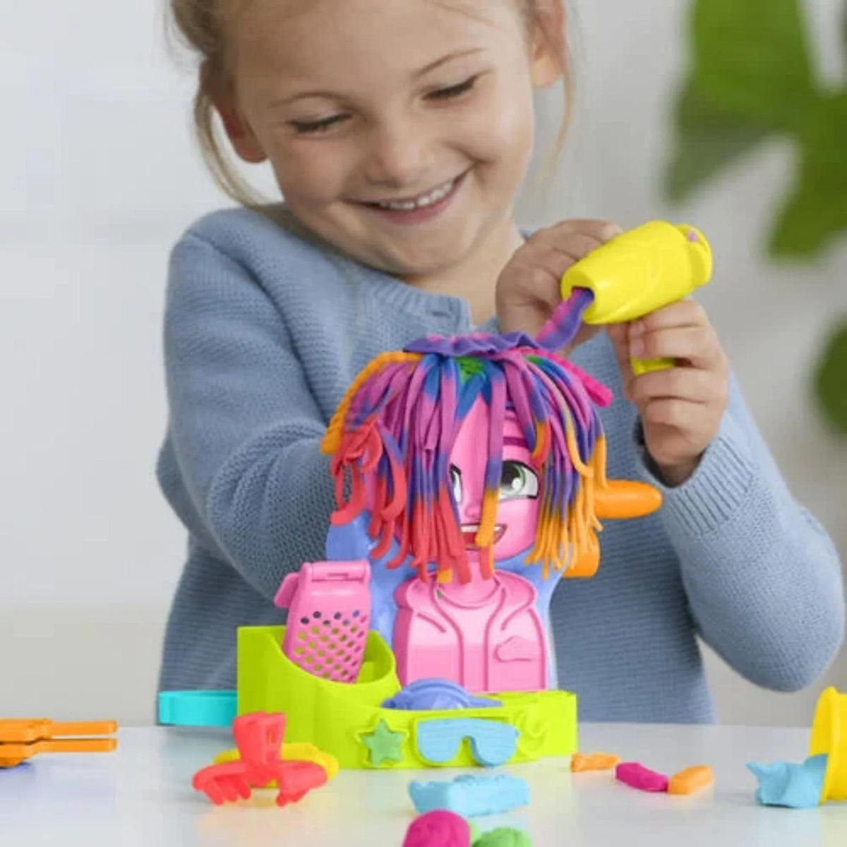 Children’s hair styling playset with bright pink/orange hair and colorful accessories
