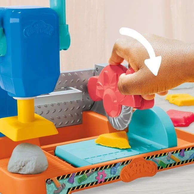 Toy dough stamping bench with blue base, red stamp, and colorful dough pieces