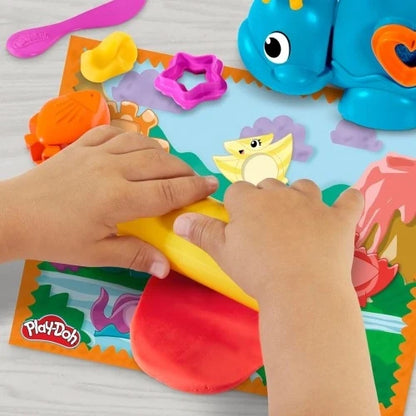 Play-Doh dinosaur dough tools and shapes on mat, hands pressing colorful pieces