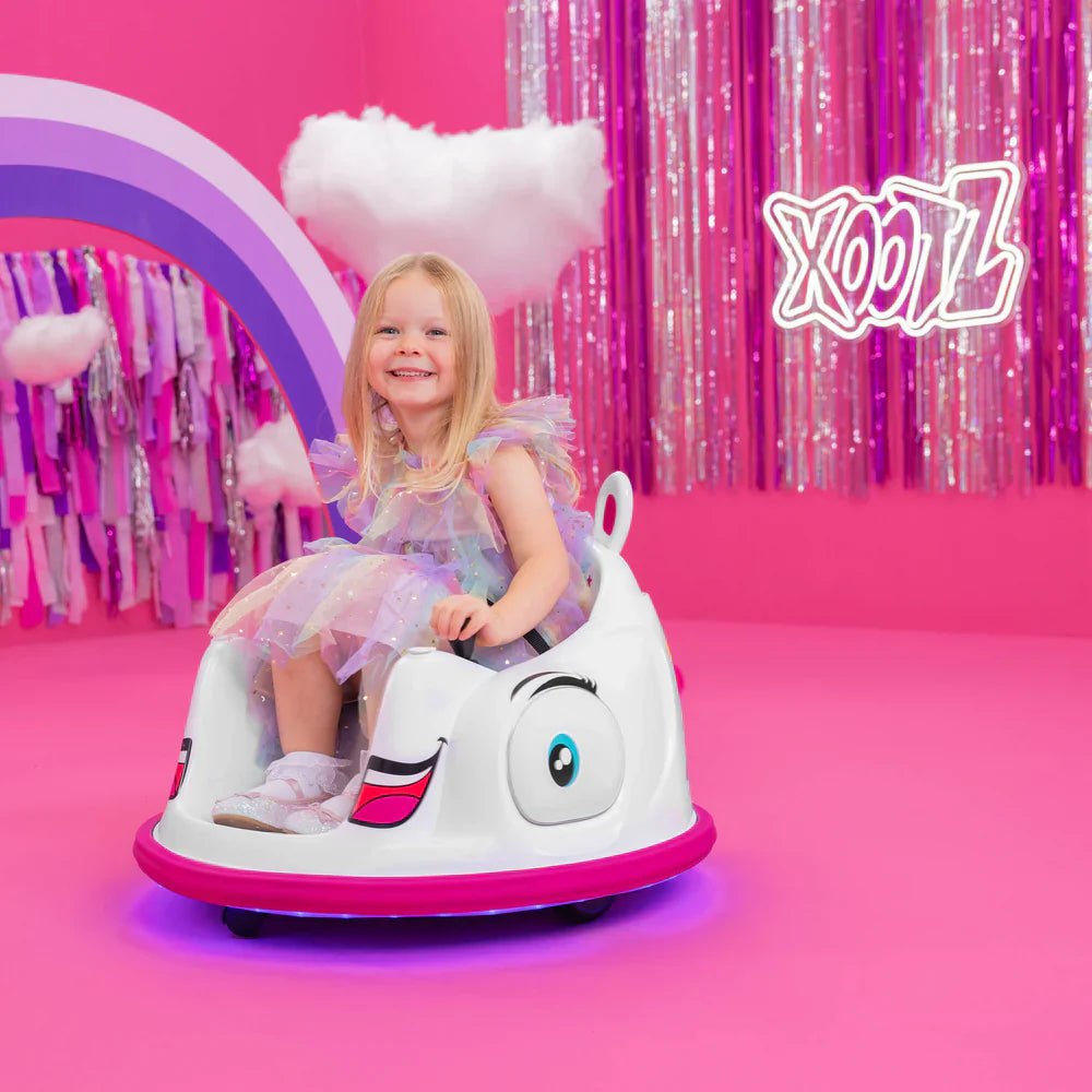 Smiling girl riding the unicorn electric bumper car, white seat with pink rim