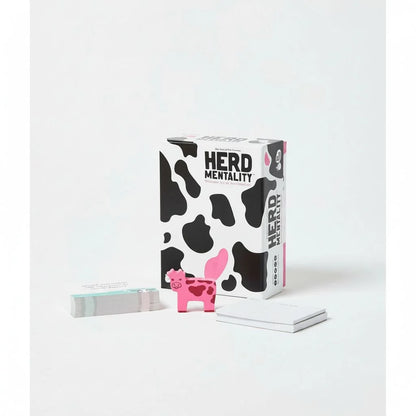 Board game box with Herd Mentality branding, cow-print pieces and card stack