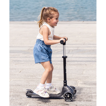 Black sparkling kids scooter with handlebar and three wheels, ridden by a child