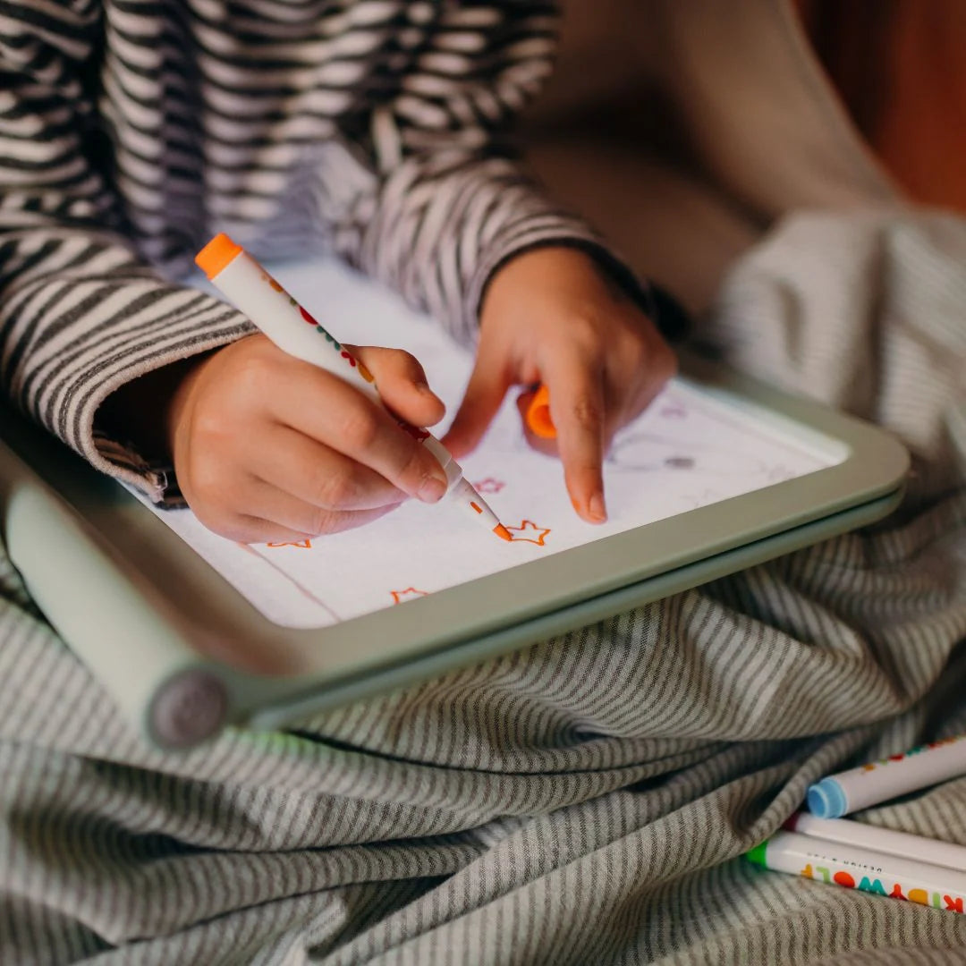 Kids marker set: hands color on a tablet with orange marker lines