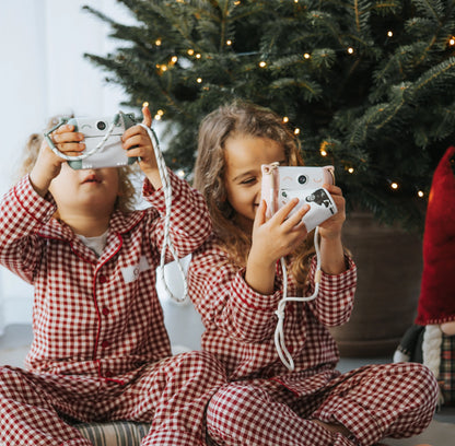 Children holding a mint green and white thermal print camera with a wrist strap