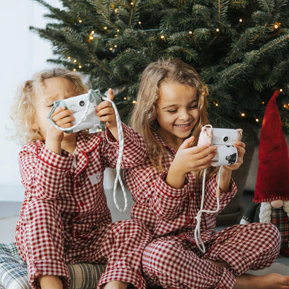 Kids using a mint green and white thermal print camera, aiming the lens outward