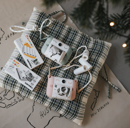 Mint green thermal print camera on a plaid fabric with printed photo strips and strap