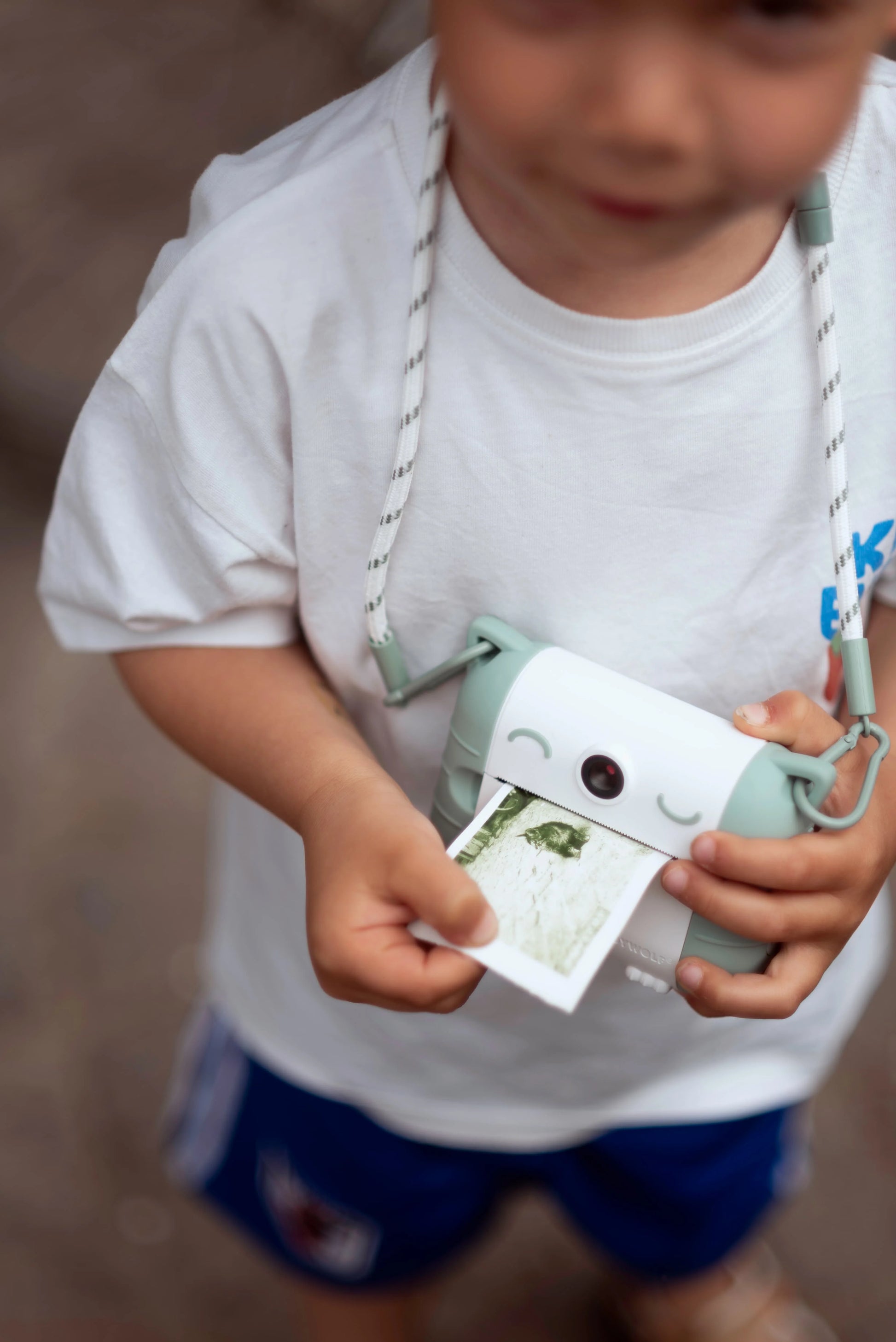 Colored photo paper strip coming out of Kidyprint camera, held by child