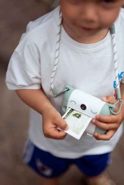 Colored photo paper strip coming out of Kidyprint camera, held by child