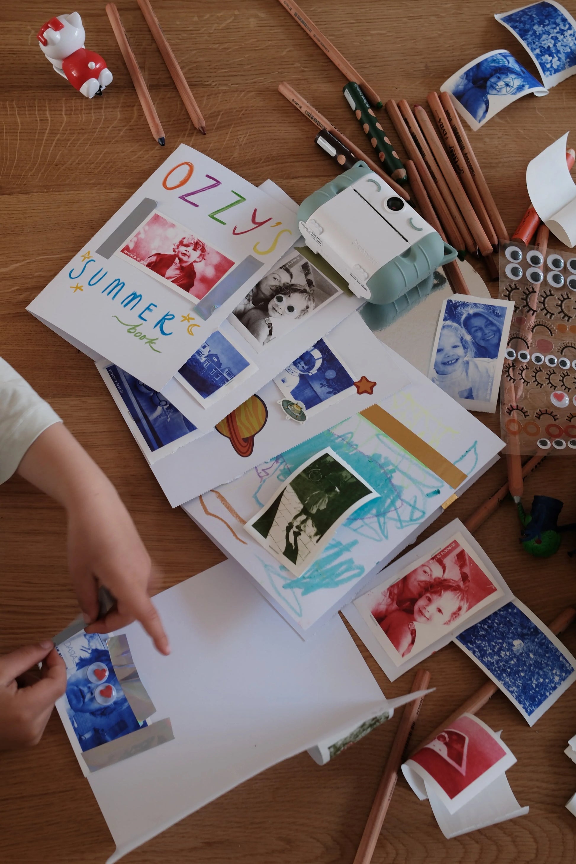 Colored photo paper strips and printed cards on table near Kidyprint camera