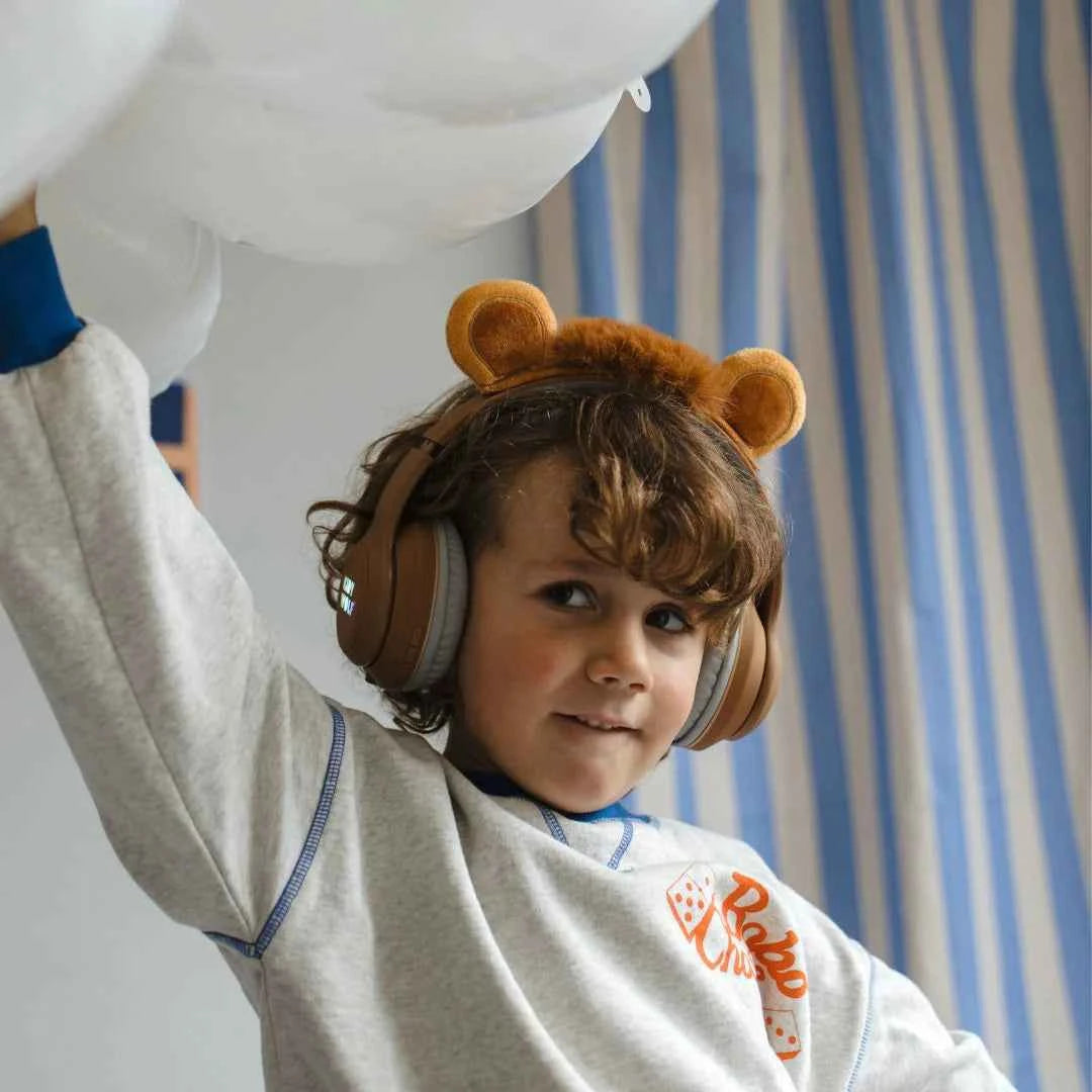 Kids' Bluetooth lion headphones worn by a child, tan ear cups and gray cushions