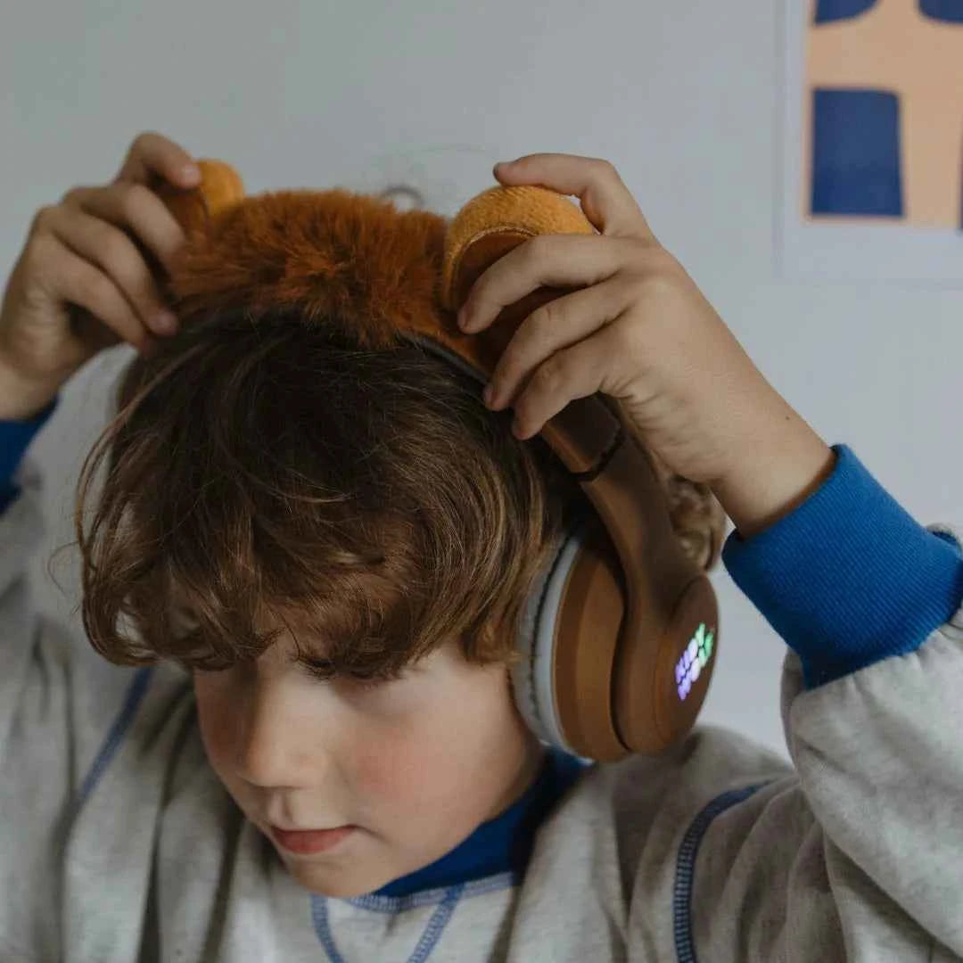 Kids' Bluetooth lion headphones close-up on child, tan ear cups with colored logo