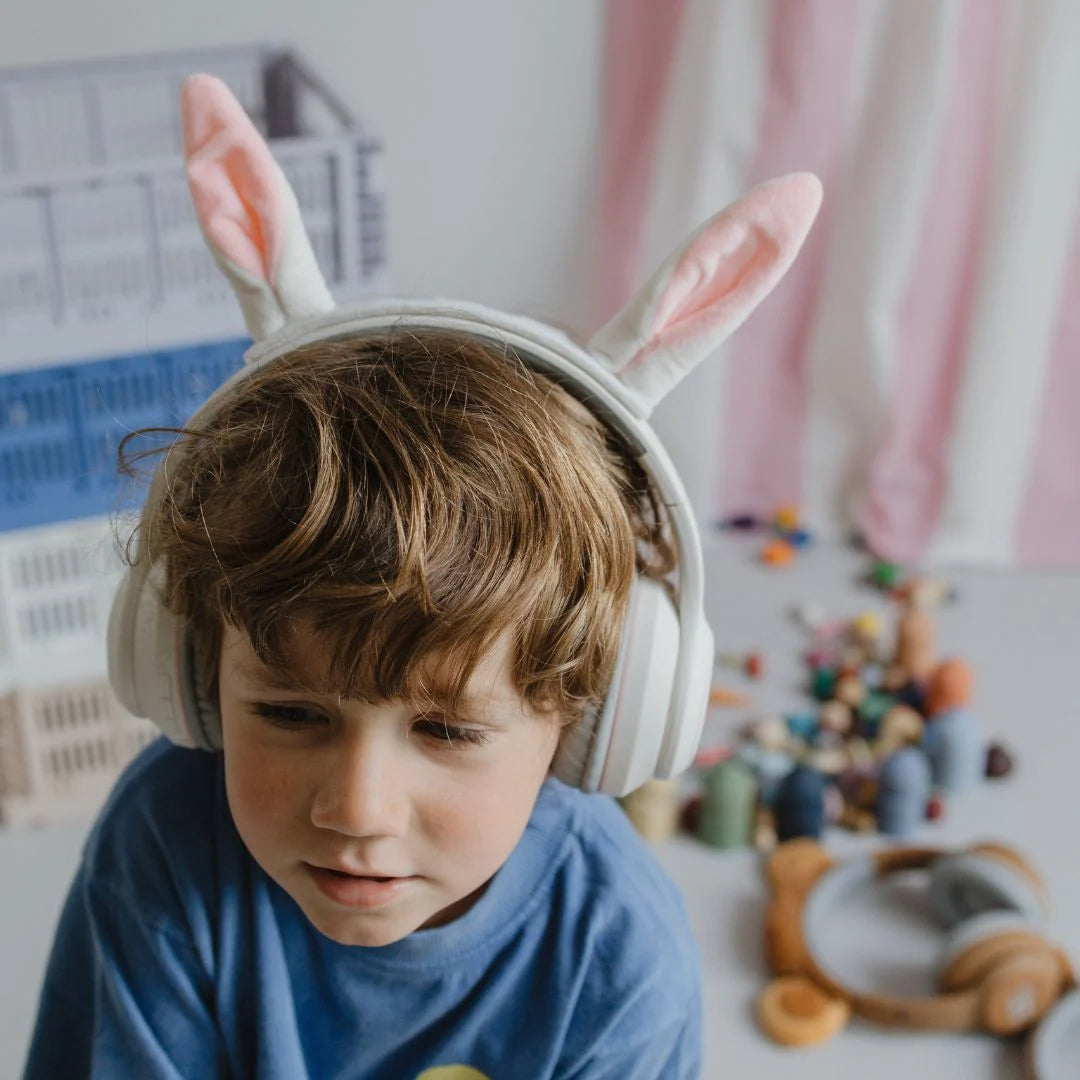 Child wearing white over-ear headphones with pink rabbit ears