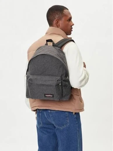 Dark denim backpack with front zip pocket, worn by a person at side