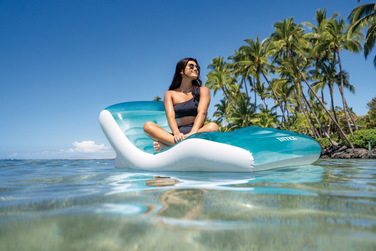 Inflatable lounge chair with turquoise panels and white headrest, person seated
