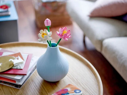 Lotus flowers bouquet with pink blooms in a light blue ridged vase