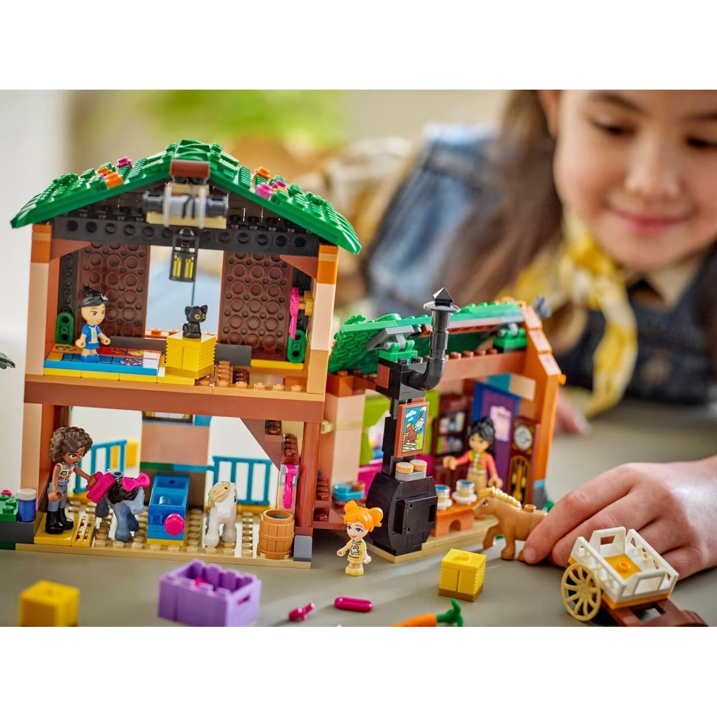 Child placing pieces in Pony Ranch & Stable playset with minifigures and animals