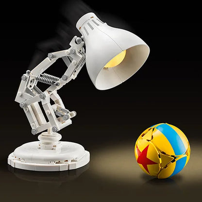 White articulated desk lamp with large shade and warm yellow bulb beside a globe ball
