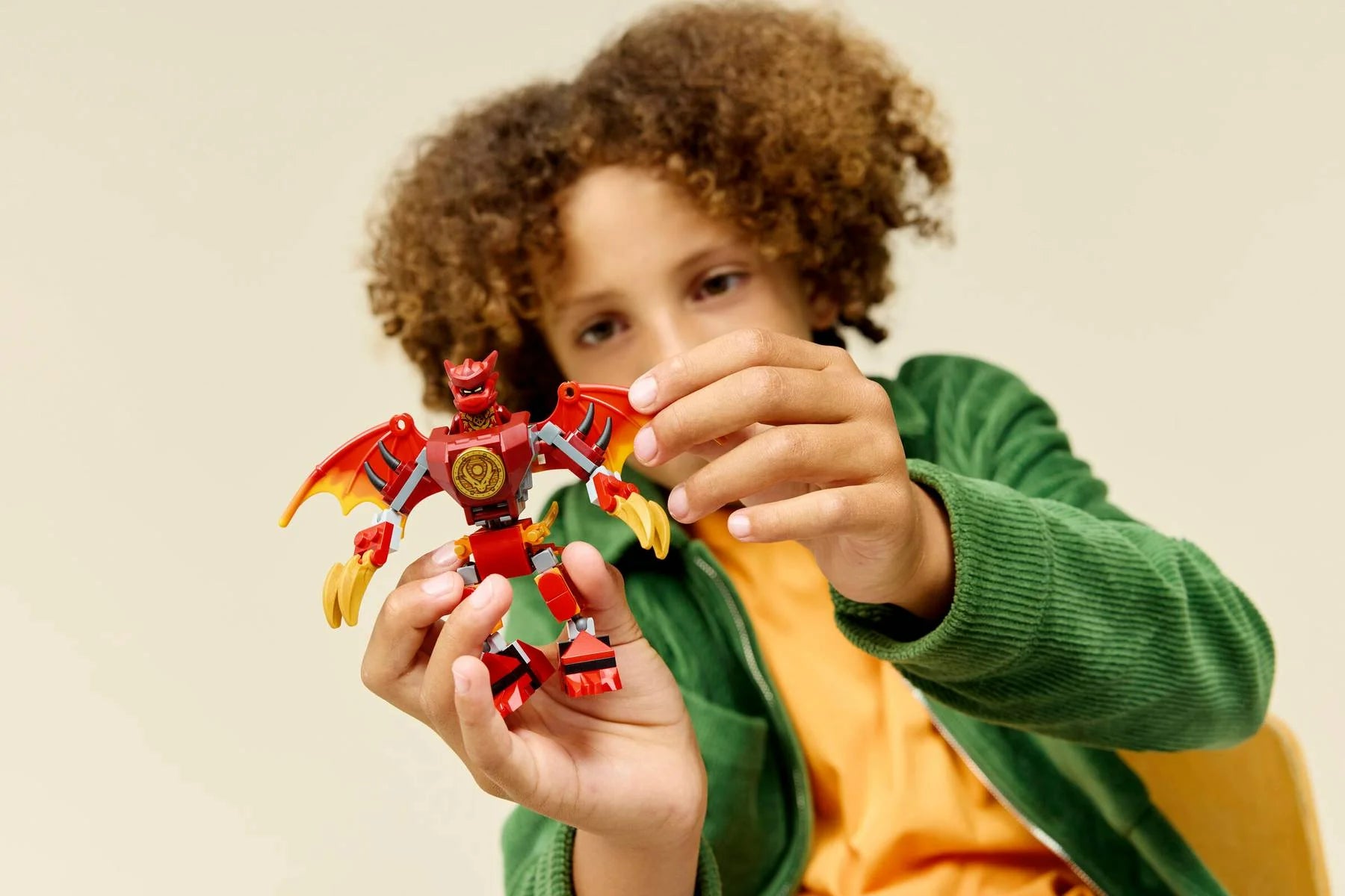 Child holding red dragon mech set pieces and ninja minifigure