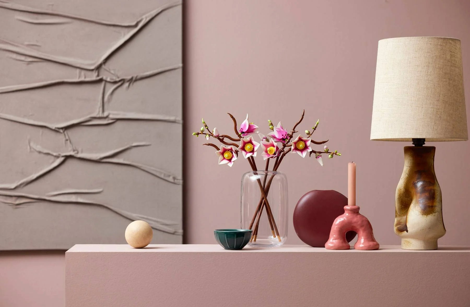 Magnolia branches in glass vase: pink flower studs with yellow centers