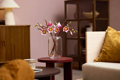Magnolia branches bouquet on table in clear vase, pink flowers with yellow centers