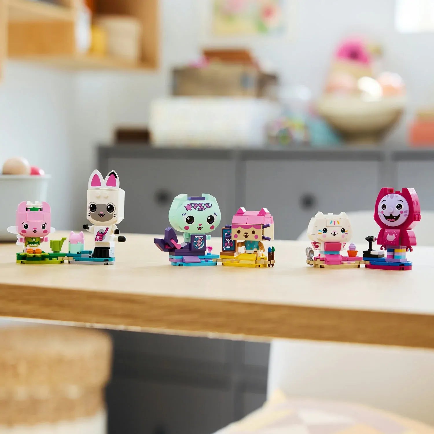 Brick-built cat friends figures on blue bases: pink, white, and black cat characters